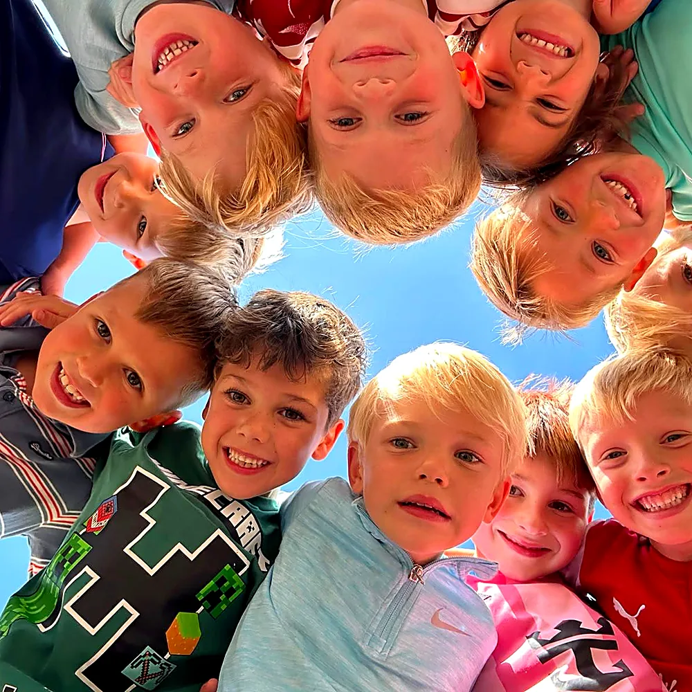 Children in a team huddle against a blue sky