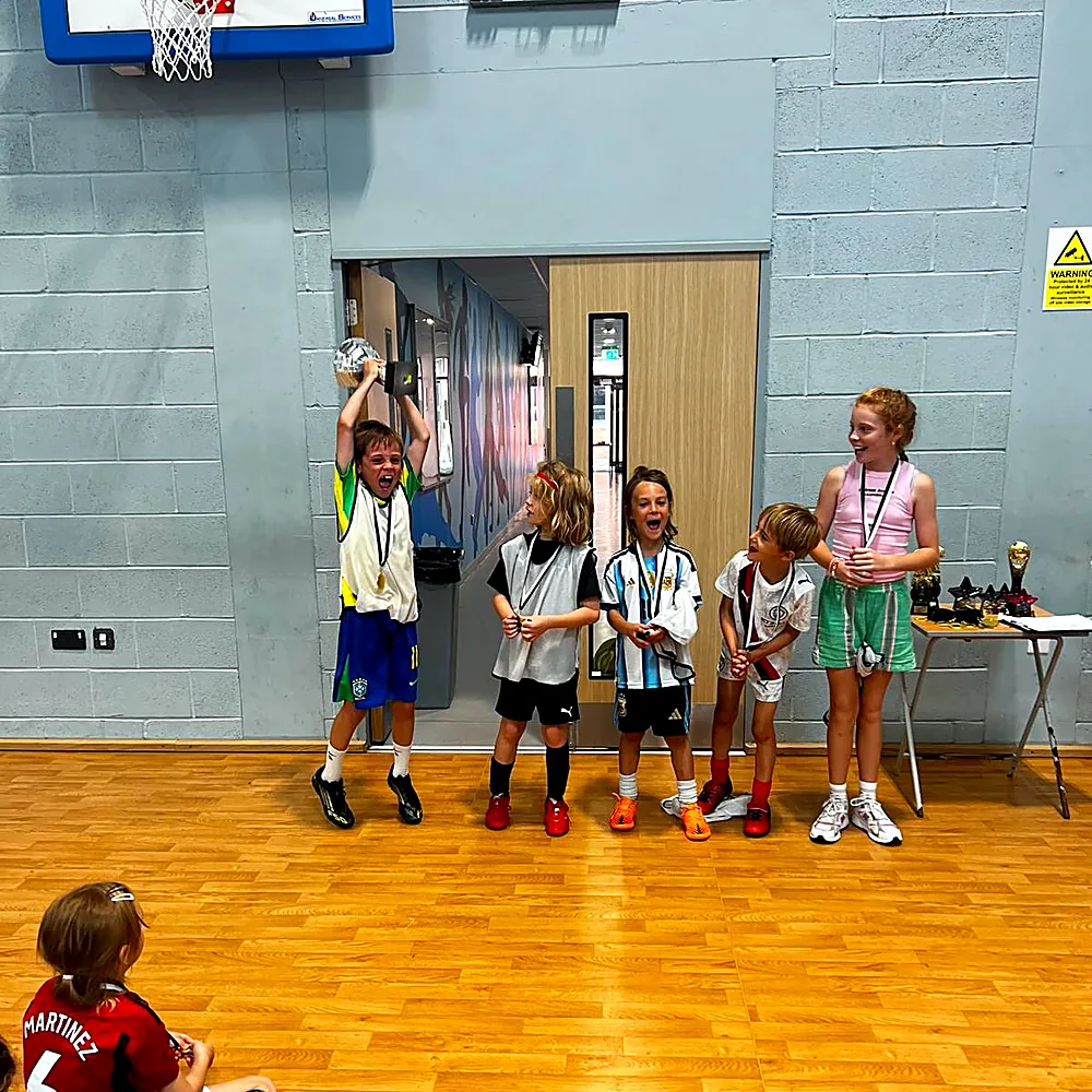 A young player lifting the trophy at a camp tournament
