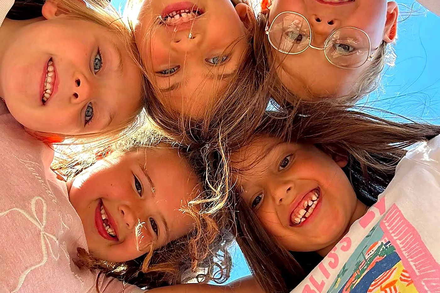 Five girls in a huddle smiling down at the camera at a Milligan & McCann session