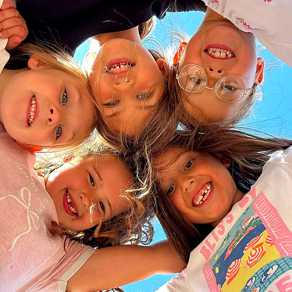 Five girls in a huddle smiling down at the camera